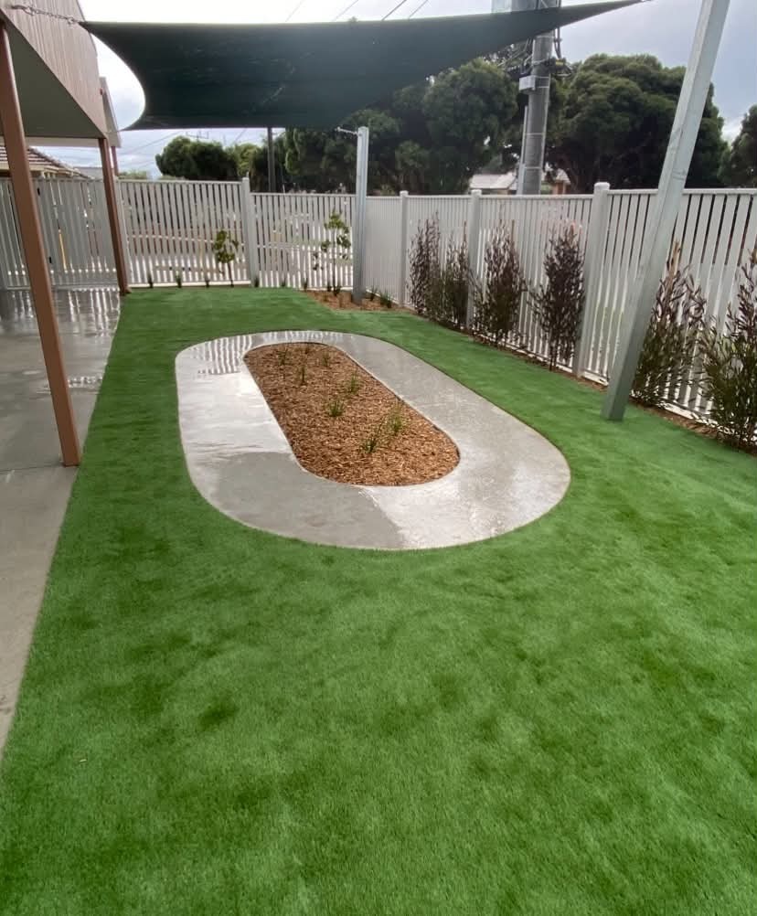A purpose-built early learning outdoor space with synthetic turf, a custom pathway loop, sensory planting, and shaded areas designed for safe exploration and active play.
